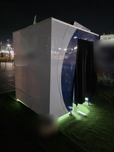곡선형 맞춤 디자인 부스 측면 — 흰 곡면 판넬과 파란 앞면, 아래쪽 조명