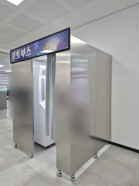 우주 캐릭터 그림의 '포토부스' 조명 간판을 단 스테인리스 맞춤 부스 — 실내 로비